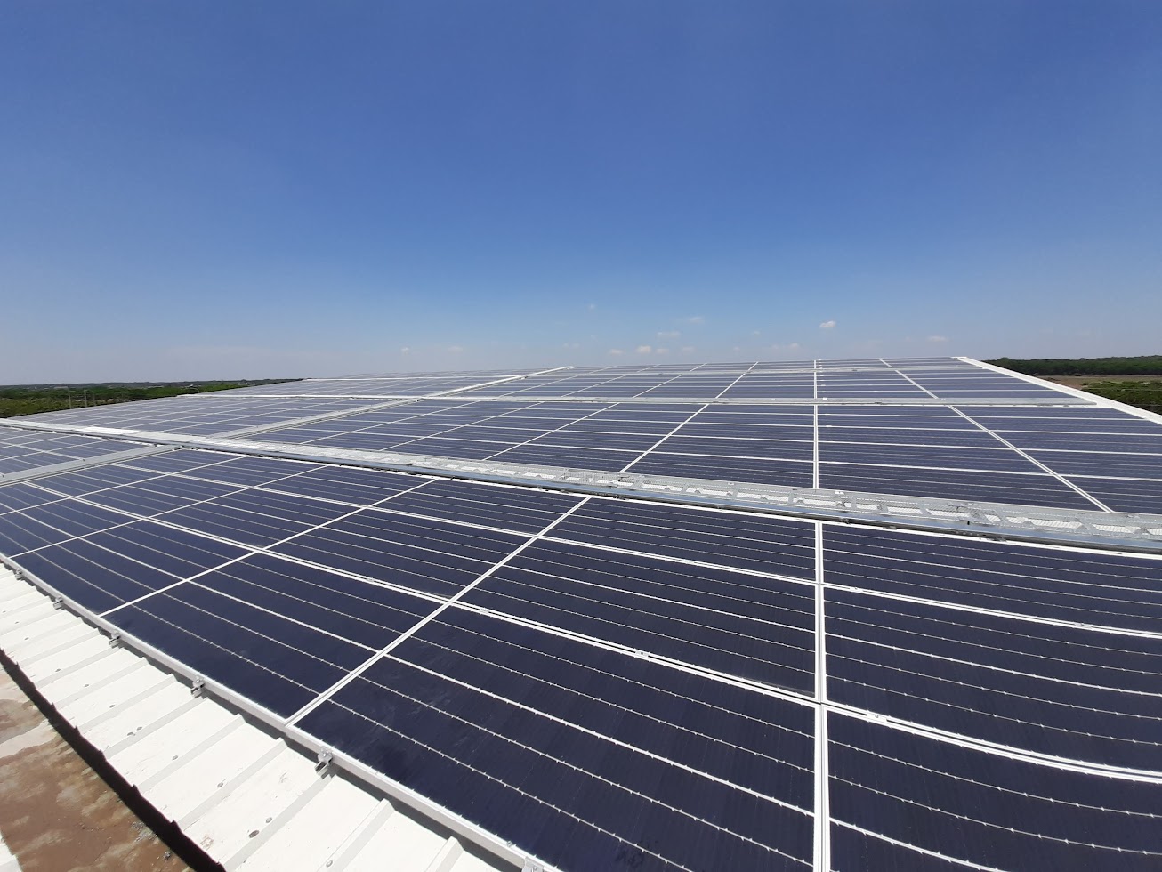 Large solar panel array installed on an industrial rooftop under a clear blue sky