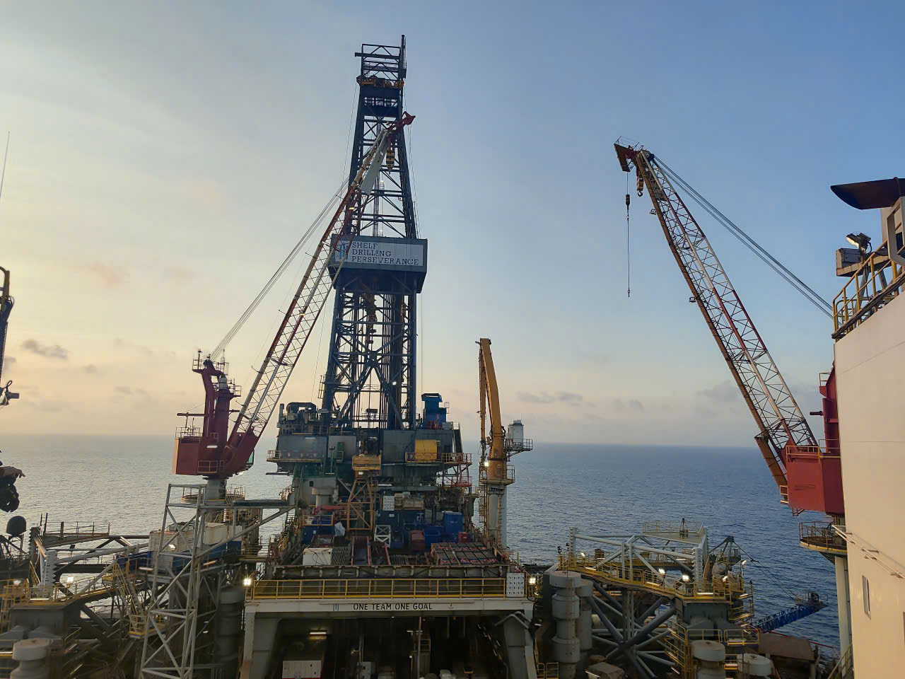 Offshore jack-up drilling rig Shelf Drilling Perseverance at sea at sunrise with cranes and derrick